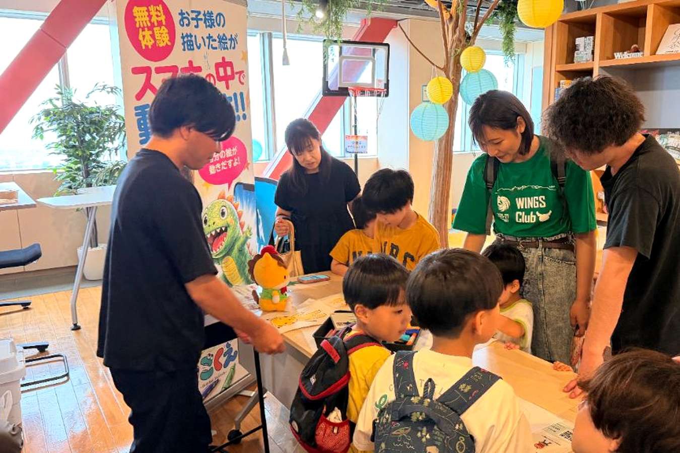 うごくえのブースに集まり、おえかきを楽しむ子どもたちと見守る大人たち